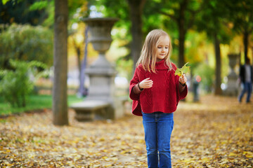 Adorable preschooler girl enjoying nice and sunny autumn day outdoors