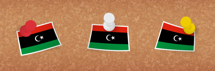 Libya flag pinned in cork board, three versions of Libya flag.