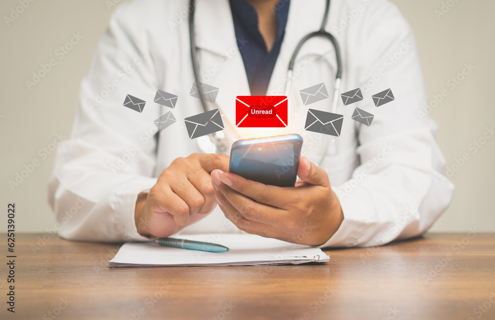 Poster doctor using a mobile receives a new message with unread email icons while sitting at the table.