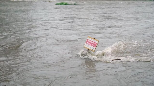 豪雨の日の川で堪える木の看板
