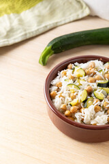 Basmati rice salad bowl with chickpeas and zucchini, served on a wooden background. Complete vegan dish quick to cook.