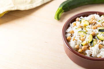 Basmati rice salad bowl with chickpeas and zucchini, served on a wooden background. Complete vegan dish quick to cook.