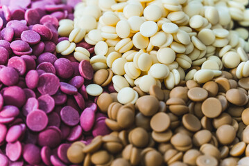 Closeup shot of chocolate chips of different colors. Confectionery concept. Stack of ruby, white and dark chocolate chips. High quality photo