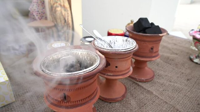 Small metal decorative Arabian Bakhoor incense burner emitting white smoke - aloeswood, essential oil and burning incense chips