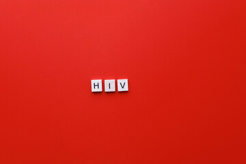 HIV Day. AIDS Day. Flatly inscription hiv from wooden letters on a red background - obrazy, fototapety, plakaty