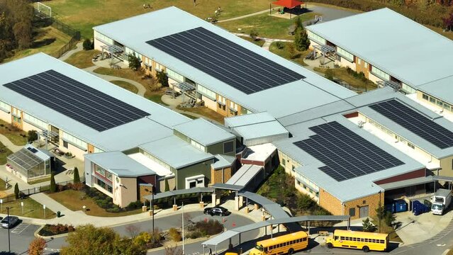 Roof of american school building covered with photovoltaic solar panels for production of electric energy. Renewable energy concept