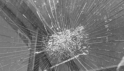 Crack on glass from impact black and white. Damaged glass in cracks from impact. - obrazy, fototapety, plakaty