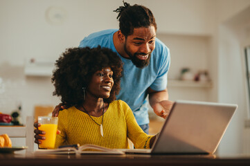 A happy casual african american businesswoman is showing a project to her supportive husband who is...