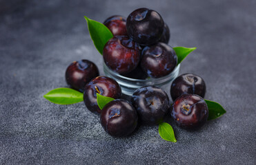 Sweet plums on dark background. Fresh blue plums with leaves. Food fruit Background. Summer postcard. Harvesting in garden, Harvest of plum
