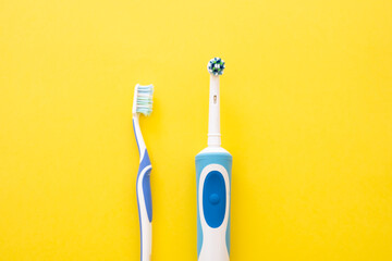 Electric and analog toothbrush in blue on a yellow background