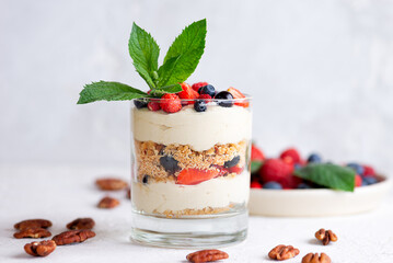 Trifle dessert in a glass with berries, mint, whipped cream and biscuit. Healthy food, vegan, sugar, gluten and lactose free.