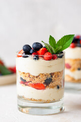 Vegan trifle dessert in a glass with berries, mint, whipped cream and biscuit. Healthy food, sugar,...