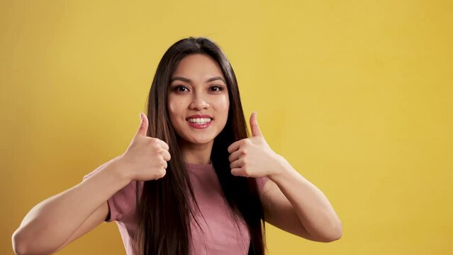 Asian Girl with a confident smile in a studio with a thumbs up gesture - extreme slow motion shot