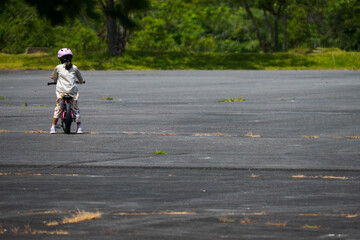 自信なさそうに公園で一人で自転車の練習をする少女