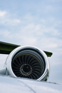 Close-up of a jet engine turbine under the wing of a modern aircraft against a cloudy sky