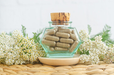 Small vintage bottle with herbal food supplement capsules and yarrow flowers. Natural healthcare, herbal medicine, skincare and beauty treatment.