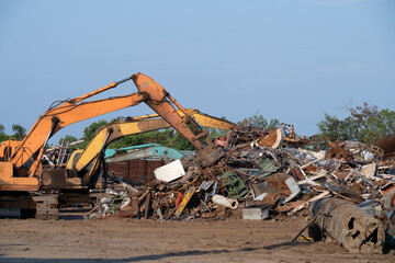 Excavator magnet lifting steel scraps from recycling materials pile at scrap yard in recycling factory. Excavator with electro and magnetic sucker magnet chuck. Special excavator. Scrap metal magnet.