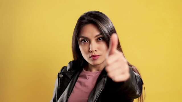 Asian Girl in a studio does a thumbs-up gesture - extreme slow motion shot