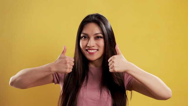 Asian Girl with a confident smile in a studio doing a thumbs up gesture - extreme slow motion shot