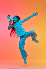 Fototapeta na wymiar Active excited child wearing casual style clothes jumping high over neon light background. Concept of childhood, emotions, kids fashion