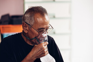 Elderly Senior Man wear oxygen inhaler device for helping breath respiratory. Patient use portable...