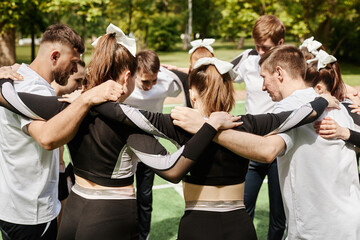 Cheerleader team standing in circle and saying the words of support to each other before competition