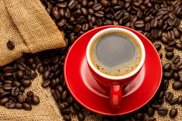 Black coffee or hot tea in a red coffee cup cappuccino espresso Breakfast with coffee beans on wooden table Isolated on black background. Top view.