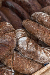 Lots of round dark bread on the counter. Traditional pastries. Close-up. Selective focus. Vertical.