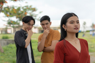 An unsettled young asian woman tries to ignore two men checking out her body or catcalling.