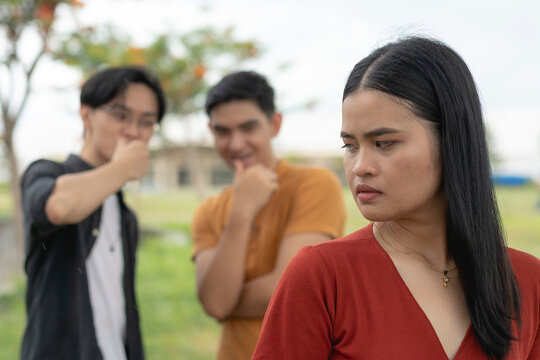 A young asian woman feels unsettled and annoyed after noticing two men checking out her body or catcalling. Sexual harassment and objectifying women.