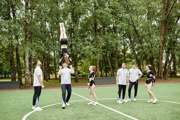Cheerleading team practicing in tricks together outdoors during sport training