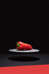 Pimiento rojo fresco sobre un plato de pizarra y fondo negro	