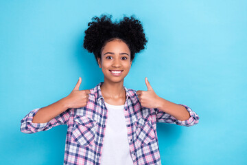 Photo of good mood pleasant girl with buns hairstyle wear plaid shirt two hands show thumbs up approve isolated on blue color background