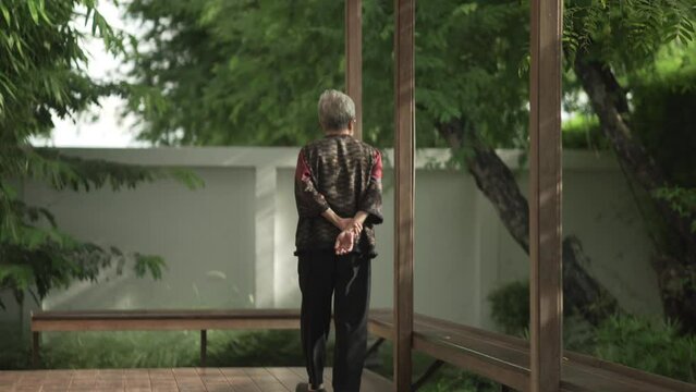 old elderly elder senior woman walking on balcony in japanese garden