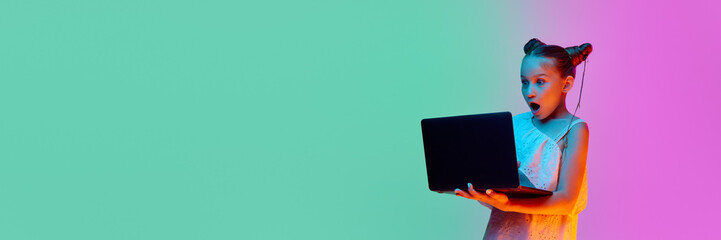 One smart, schoolage little girl, child posing with laptop against gradient pink-blue background....