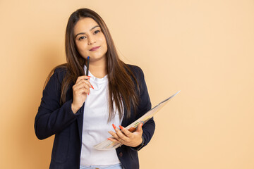 young indian woman wearing formal suit holding notebook and pen thinking of something isolated over beige background.