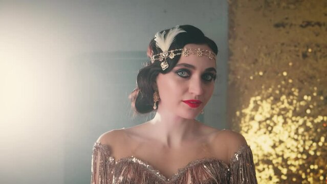 Old style 1920s video. Happy smiling face young sexy retro woman 20s. professional makeup smoky eyes red lips salon hairstyle. Portrait beauty Girl in vintage evening golden dress headband earings
