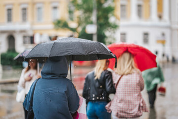 People under umbrellas. Rainy evening, city street at autumn. Seasons, weather concept