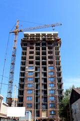 A high-rise building under construction stands against the blue sky with a crane