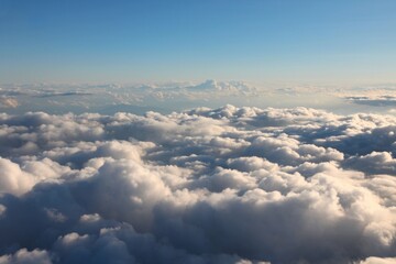Fluffy clouds aerial view. White cumulus clouds sky view from aircraft window.