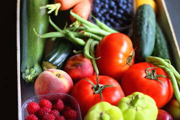 Wooden crate full of healthy seasonal fruit and vegetable. Selective focus, dark background.