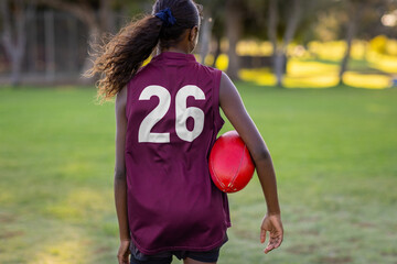 football player number 26 seen from behind with red leather football under arm