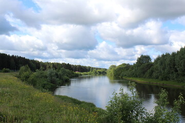 Beautiful view of a flowing river in summer with trees and fields.	