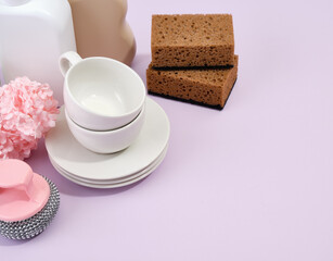 Set of clean washed dishes and cups. Dishwashing sponges on table. Copy space for text.