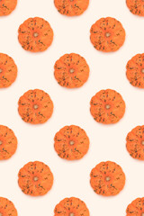 Pattern made of small orange pumpkin on a beige background.