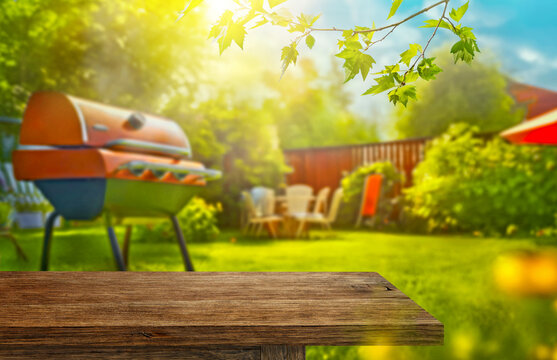 summer time in backyard garden with grill BBQ, wooden table, blurred background
