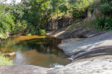 Small waterfall lake, river flowing over a large smooth block of stone, lake with clean and crystalline waters, river between mountains, Santa Maria Madalena, Brazil
