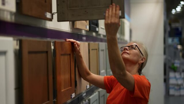 Pretty mature woman looking at cabinet doors for kitchen and bathroom in a hardware store.