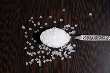 Top view of Sugar granules in spoon on the table