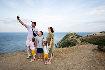 Happy family with three children taking selfie on the top of the mountain. Cape Emine, Black sea coast, Bulgaria.